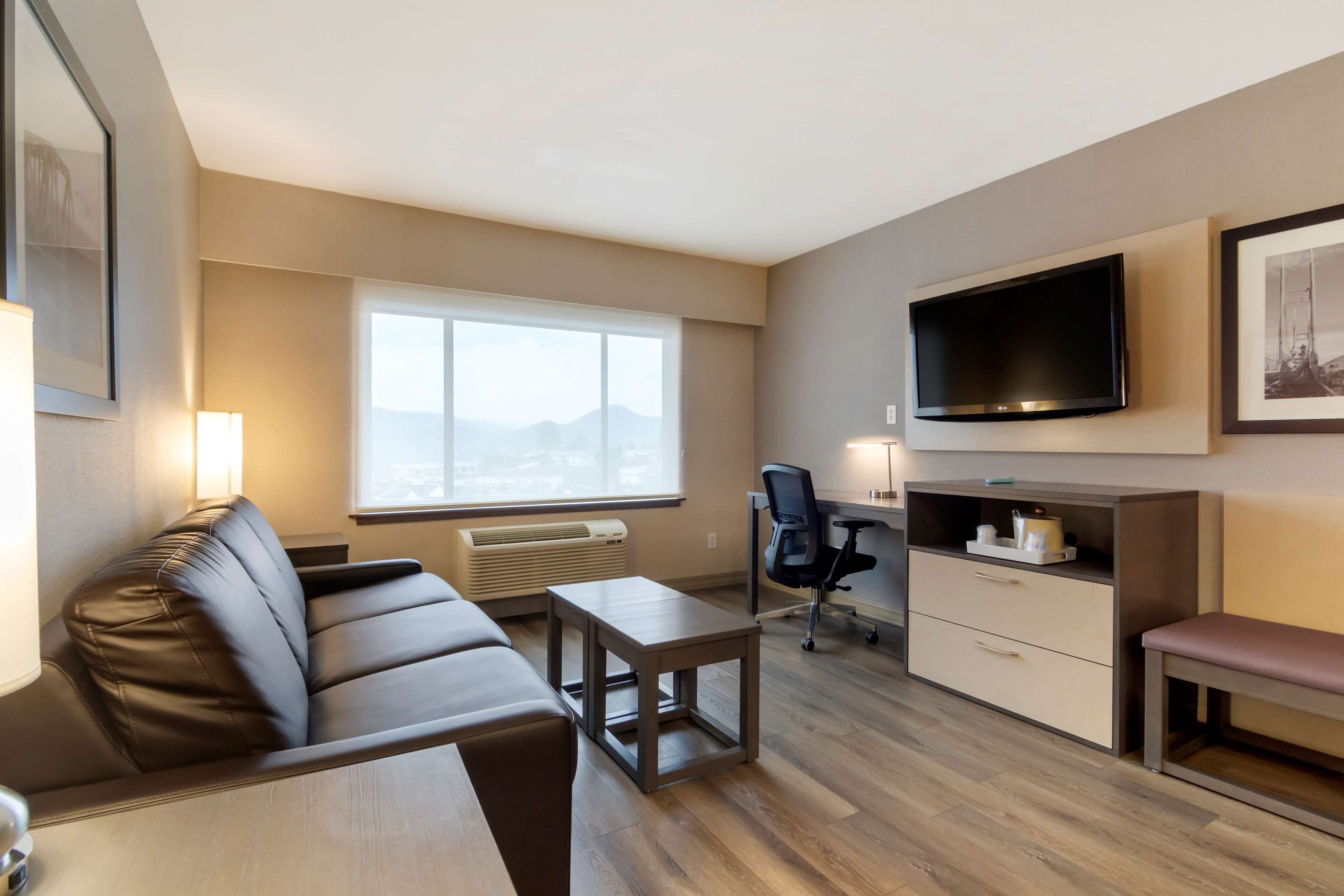 A modern living room with a sofa, a coffee table, a desk, and a television.
