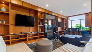 A modern living room with a fireplace, comfortable seating, and built-in shelves. - Best Western Premier Aberdeen Kamloops (Kamloops)