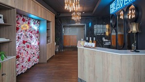 A hotel reception area with a wooden reception desk, a neon 'HEAVEN' sign, and a floral wall. - Best Western Premier Aberdeen Kamloops (Kamloops)