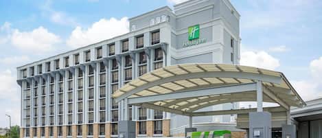 Un hotel Holiday Inn con entrada techada y estacionamiento.