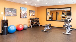 A gym with exercise equipment, dumbbells, and exercise balls.