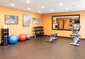 A gym with exercise equipment, dumbbells, and exercise balls.