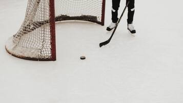 A hockey goal with netting and a puck on the ice.