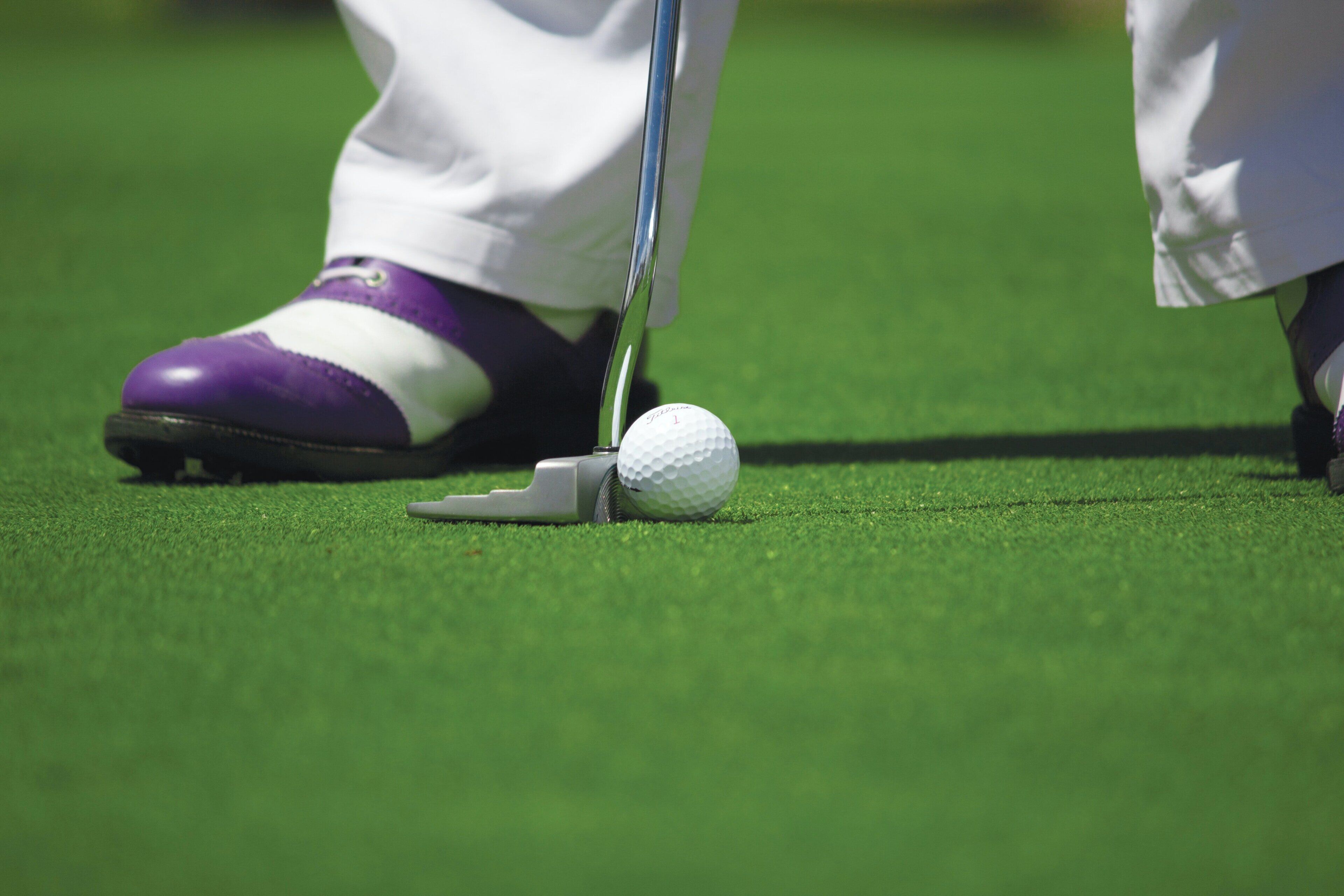 A golf ball on a tee on a green surface.
