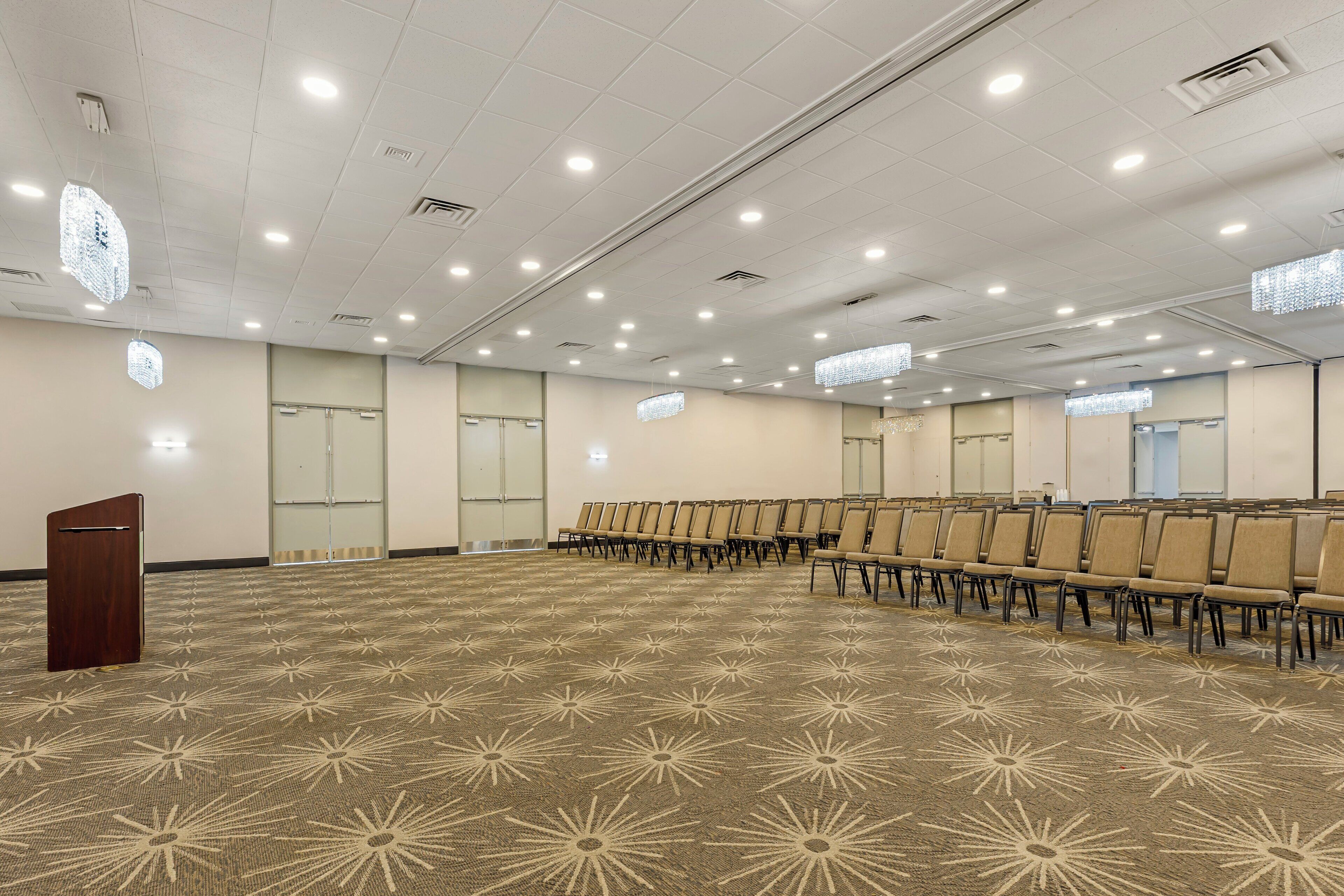 A conference room with rows of chairs, a podium, and a patterned carpet.