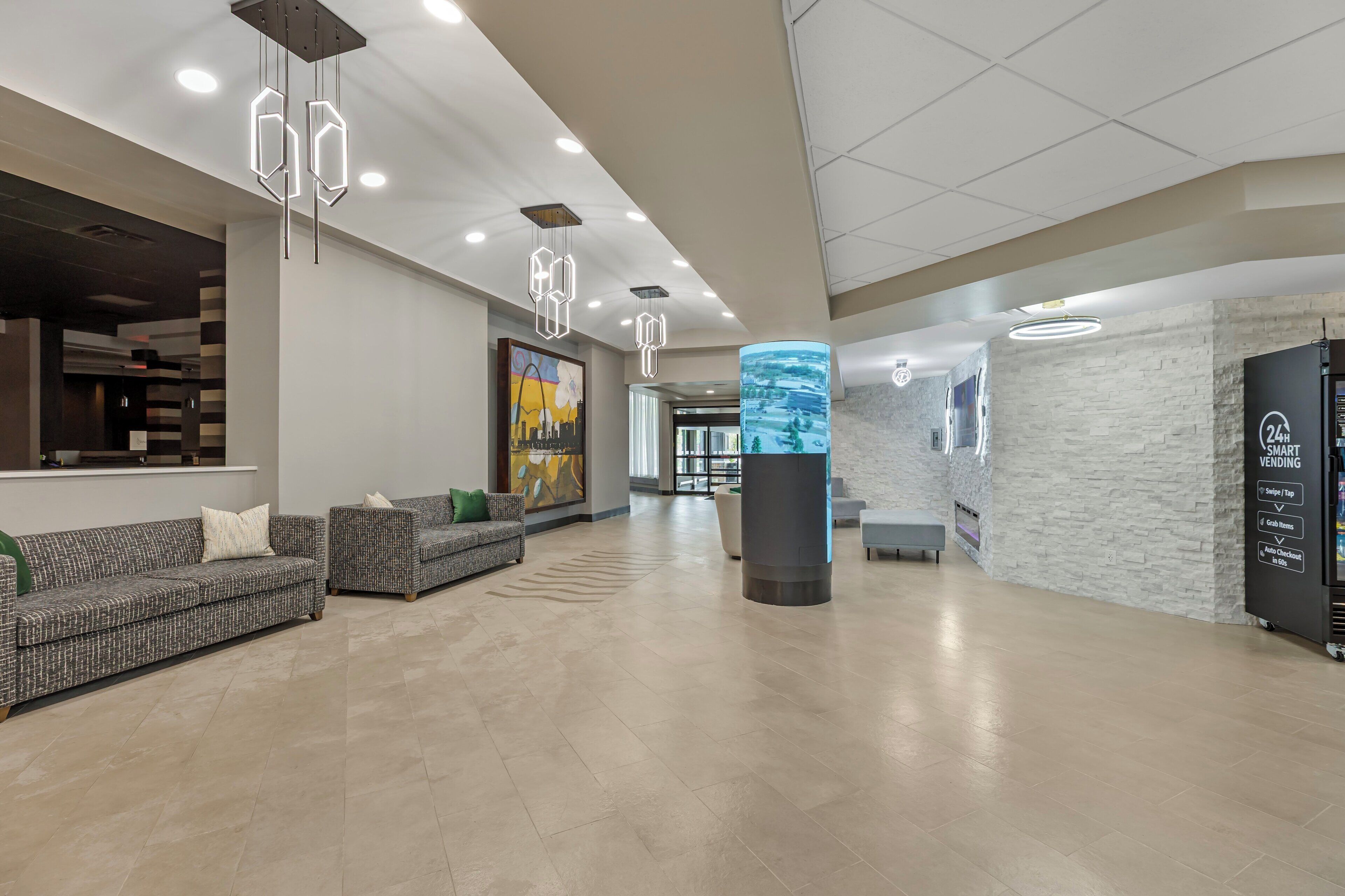 A spacious lobby with a reception desk, seating area, and a digital information kiosk.