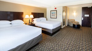 A hotel room with two beds, a nightstand with a lamp, a framed picture on the wall, and a patterned carpet.