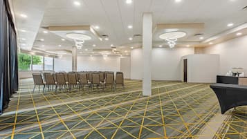 A conference room with a geometric patterned carpet, rows of chairs, and modern lighting fixtures.