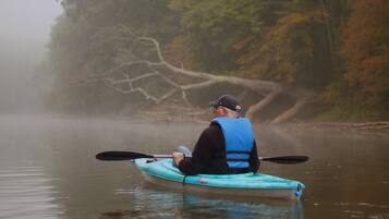 A person kayaking on a calm river surrounded by trees.