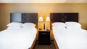 Quarto de hotel com duas camas, uma mesa de cabeceira com abajur e um telefone.