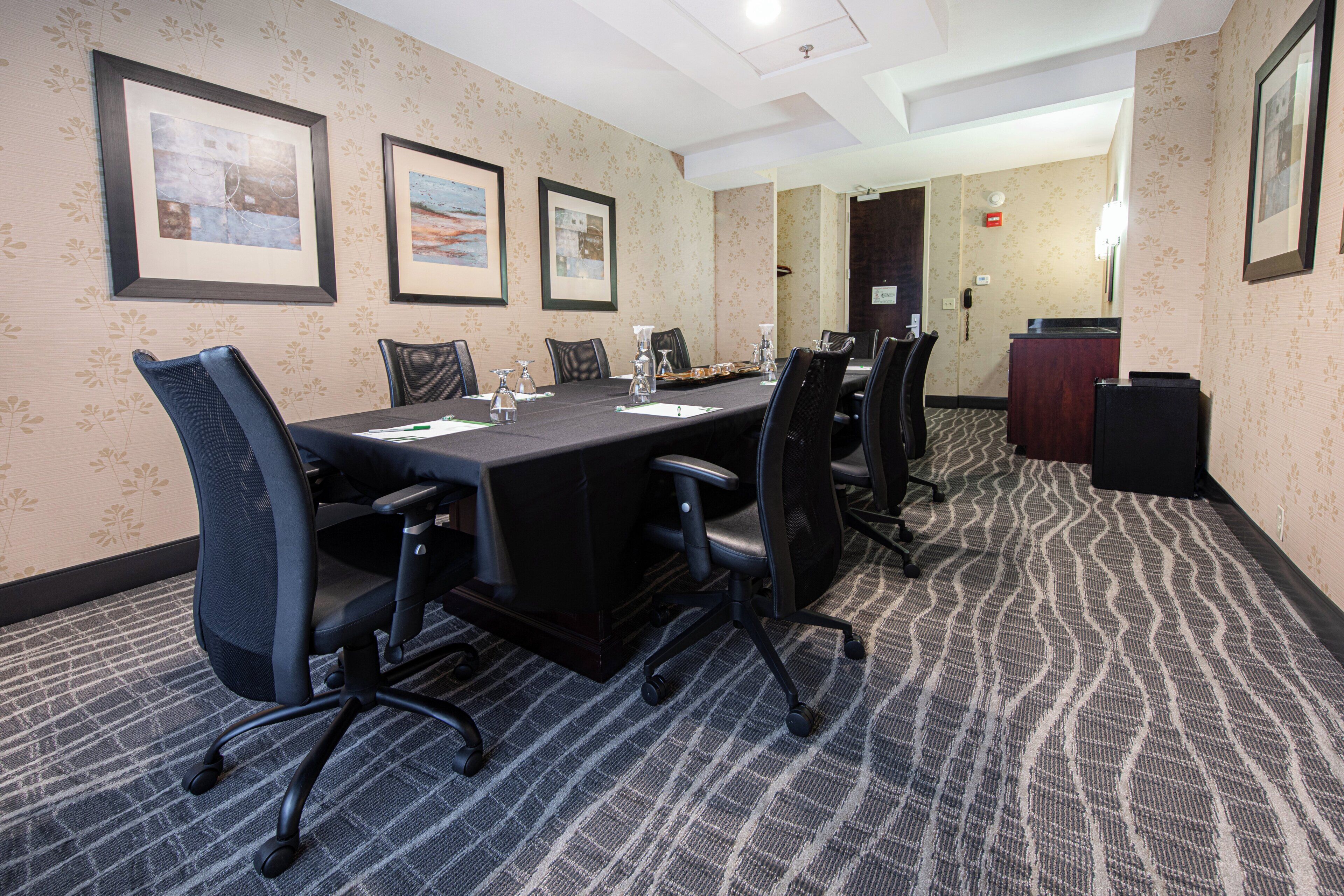 A conference room with a long table, chairs, framed pictures on the wall, and a reception desk.