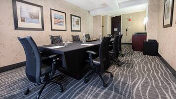 A conference room with a long table, chairs, framed pictures on the wall, and a reception desk.