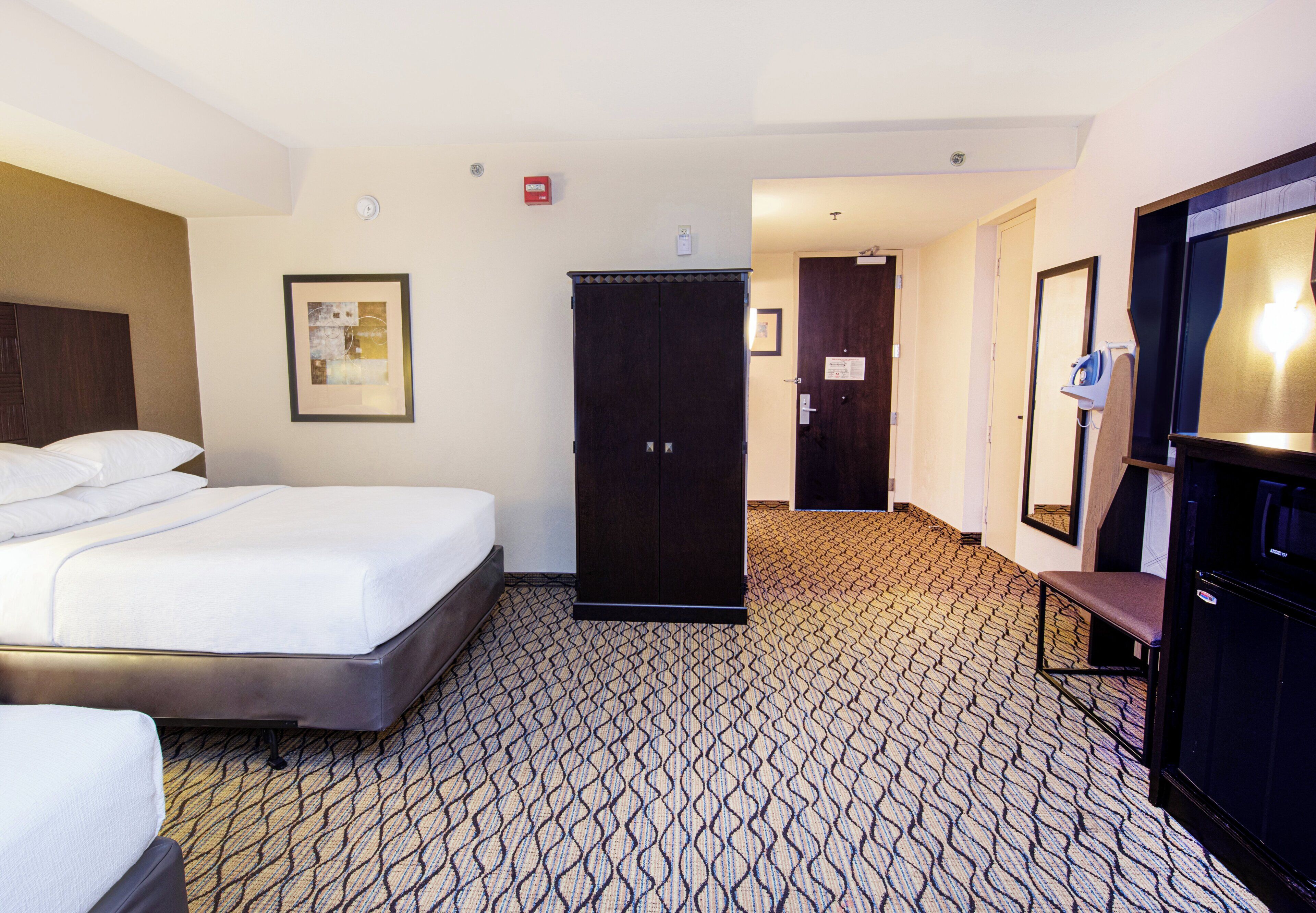A hotel room with a bed, a wardrobe, a desk with a chair, and a television.