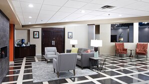 A lobby with a checkered floor, a sofa, armchairs, a small table, and a water dispenser.