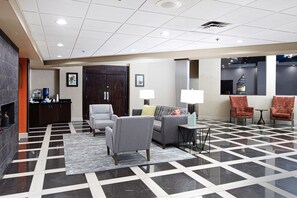 A lobby with a checkered floor, a sofa, armchairs, a small table, and a water dispenser.