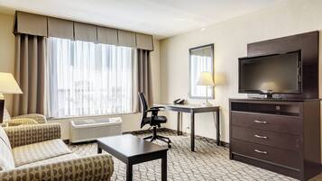 Habitación de hotel con una cama, un escritorio, una silla, un televisor y una lámpara.