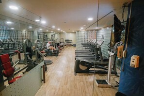 Een sportschool met diverse fitnessapparaten, waaronder loopbanden, krachttoestellen en losse gewichten.