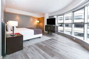 A modern hotel room with a large bed, a flat-screen TV, a desk, and a view of the city through large windows. - DoubleTree by Hilton Buenos Aires (Buenos Aires)