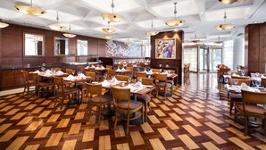 A spacious restaurant with wooden flooring, multiple dining tables, and hanging pendant lights. - DoubleTree by Hilton Buenos Aires (Buenos Aires)