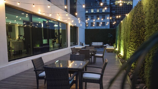 An outdoor patio with tables and chairs, string lights, and a view of the cityscape. - DoubleTree by Hilton Buenos Aires (Buenos Aires)