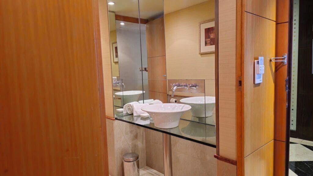 A modern bathroom with a glass partition, two sinks, and a mirror.