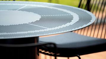 A round table with a perforated surface, likely a table fan, and a black chair with a curved backrest.