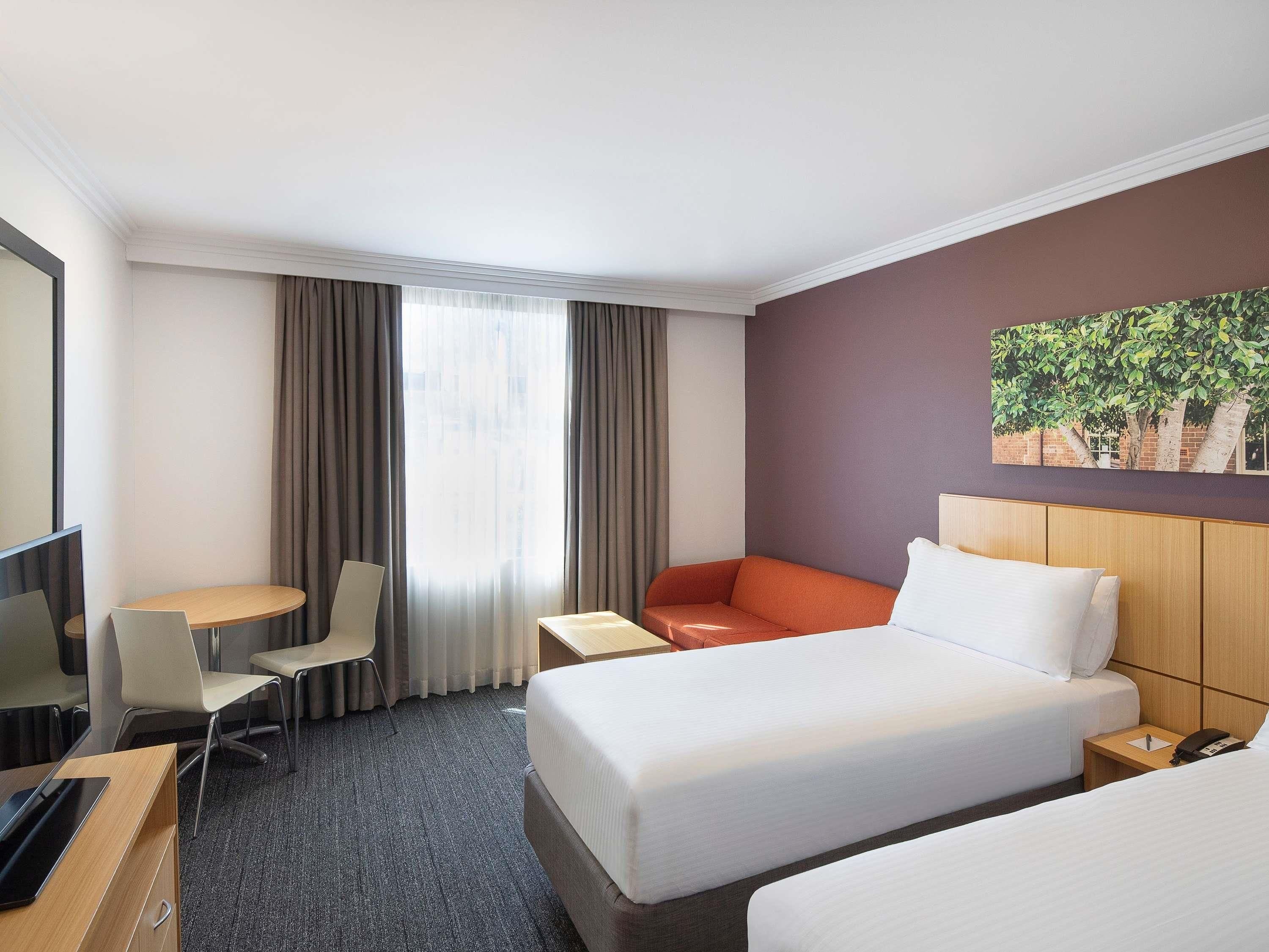 Une chambre d’hôtel avec un lit, un bureau, une chaise et une petite table.