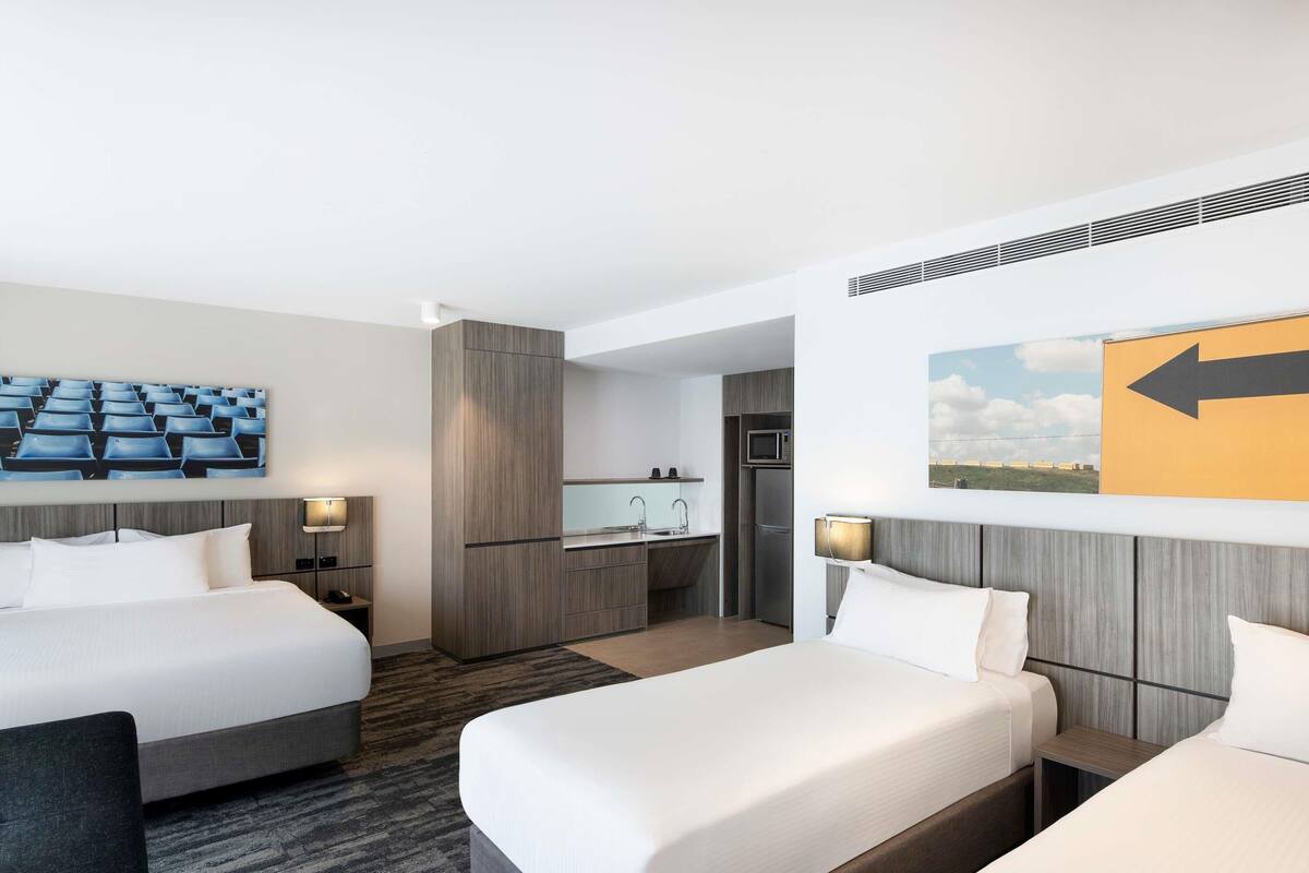 Ein Hotelzimmer mit zwei Betten, einer Küchenzeile und einem Badezimmer.