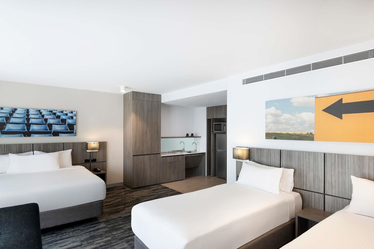 Una habitación de hotel con dos camas, kitchenette y baño.