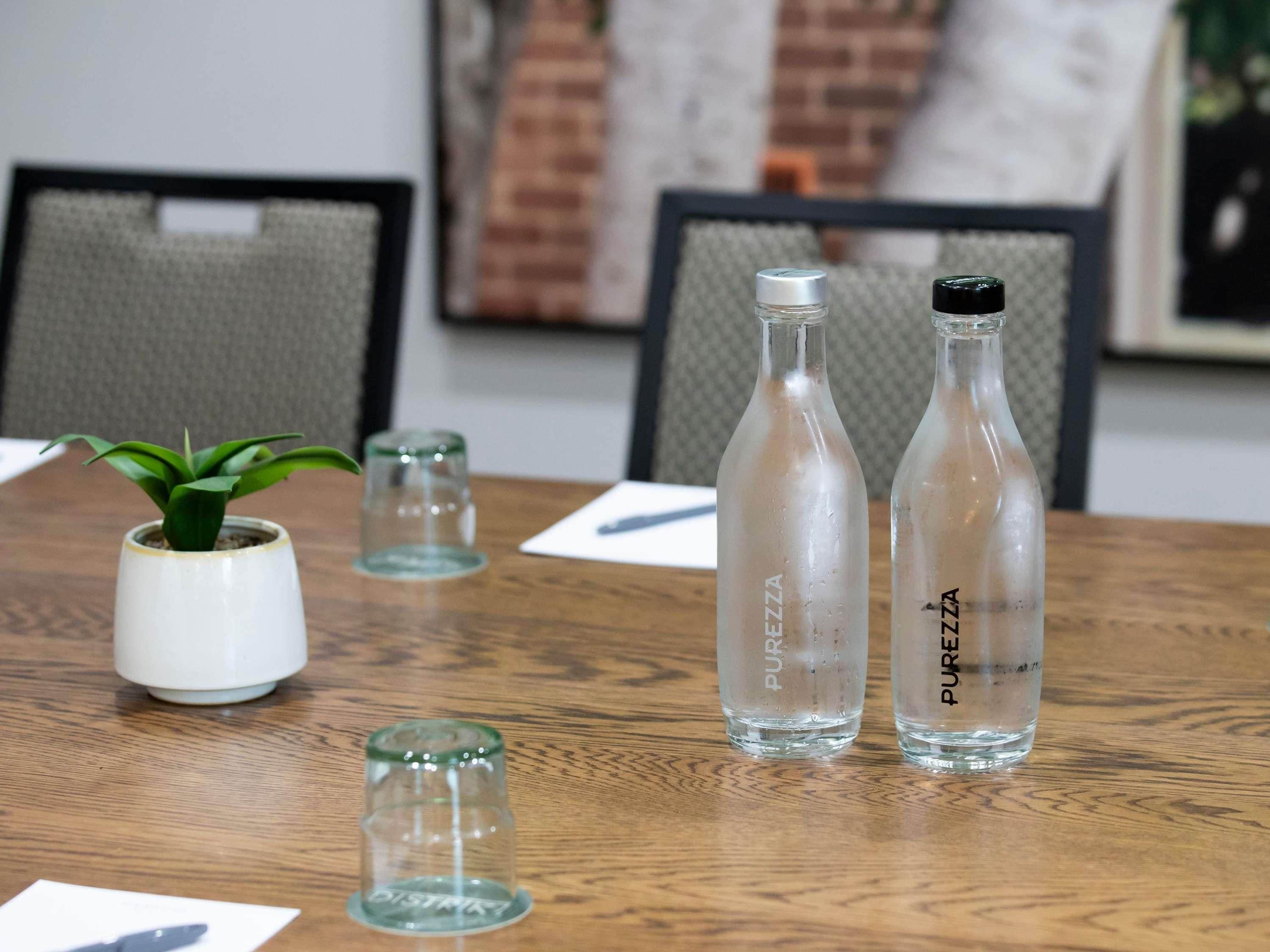 A wooden table with two glass bottles labeled 'PUREZZA' and a small potted plant.