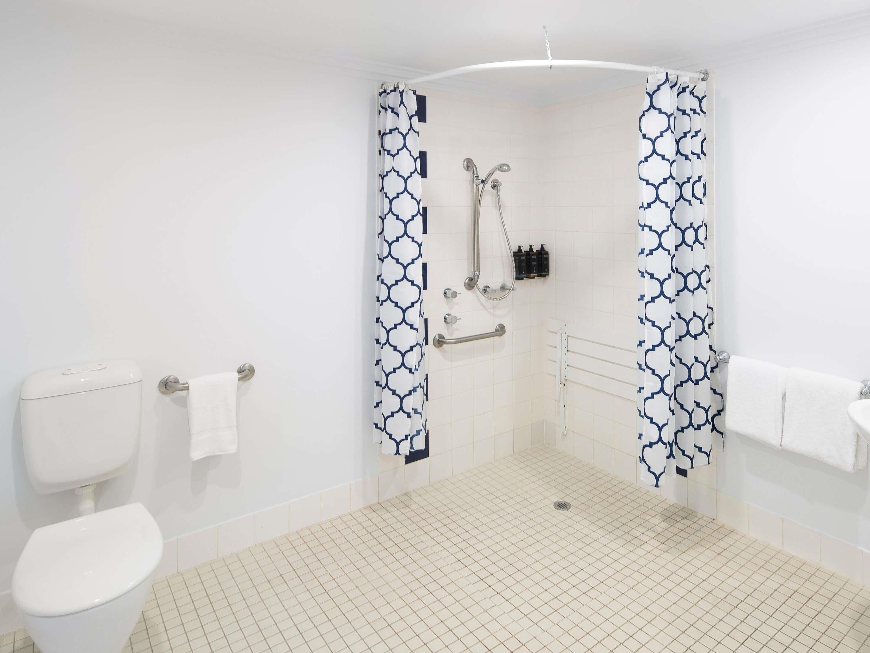 A bathroom with a toilet, a shower with a patterned curtain, and a sink.