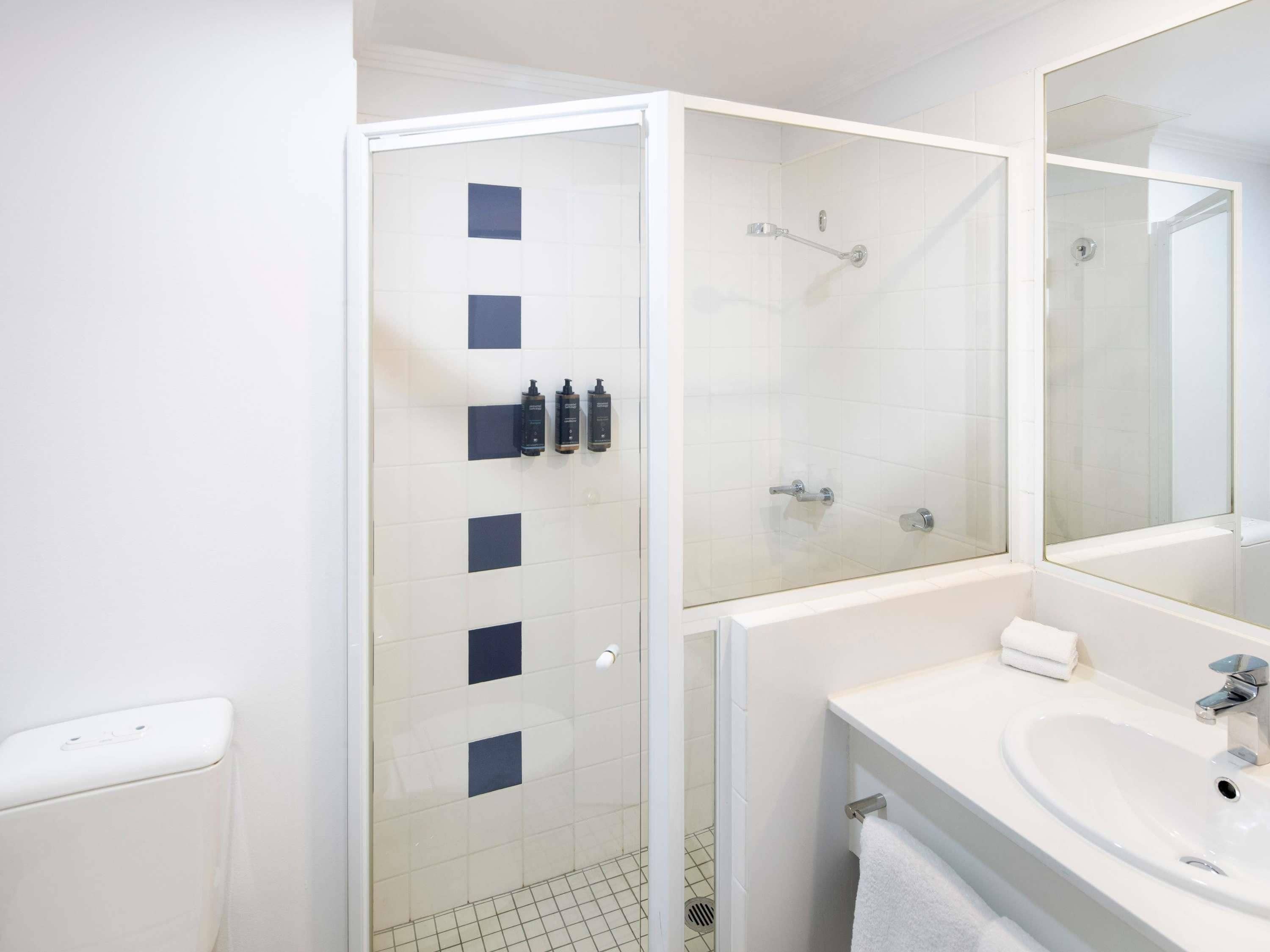 Une salle de bain moderne avec une douche à parois de verre, un lavabo blanc et un grand miroir.