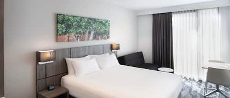 A hotel room with a large bed, bedside tables, a desk, and a chair.