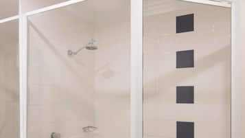 A shower enclosure with a glass door, white tiled walls, and a showerhead.
