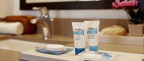 A bathroom counter with suds well shampoo and conditioner, a white soap bar, and a small blue tray.
