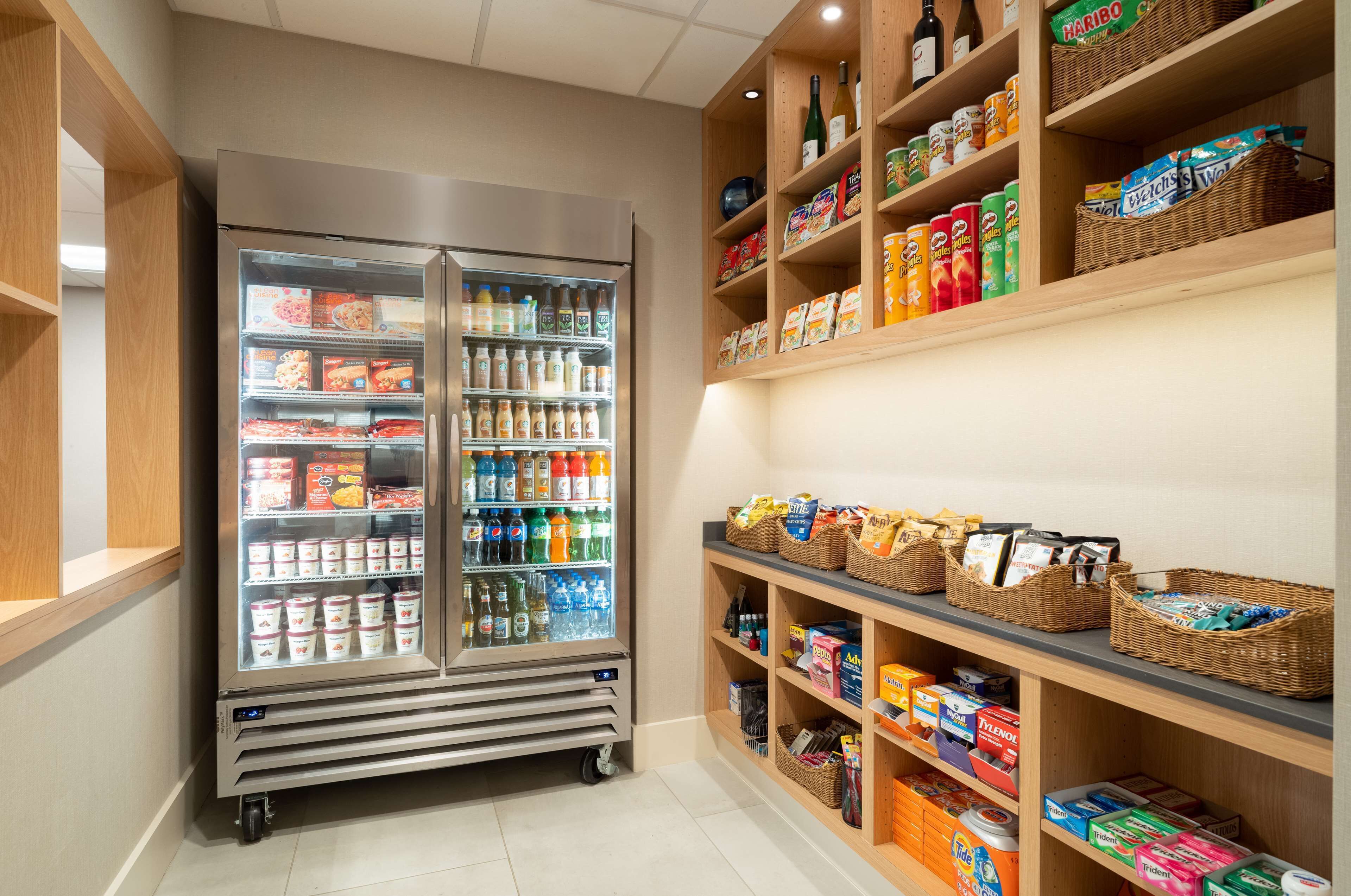 A refrigerated display case with various food items and a shelf stocked with snacks and beverages.