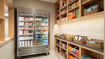 A refrigerated display case with various food items and a shelf stocked with snacks and beverages.