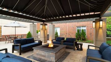 An outdoor patio with a fire pit, blue sofas, and wicker furniture.