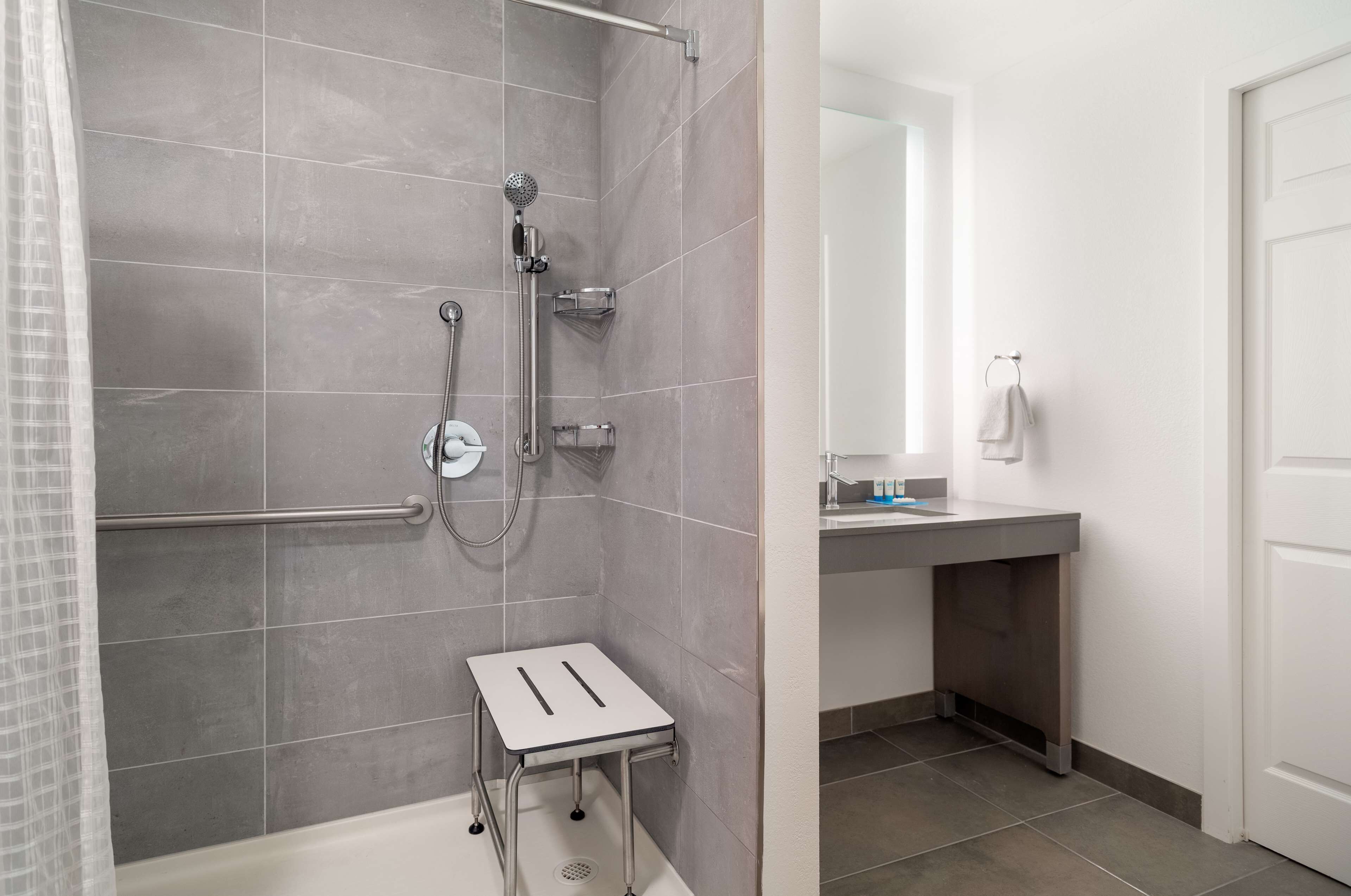 Une salle de bain avec une douche, une petite table et un lavabo équipé d’un porte-serviettes.