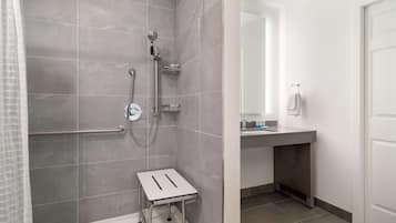 Une salle de bain avec une douche, une petite table et un lavabo équipé d’un porte-serviettes.