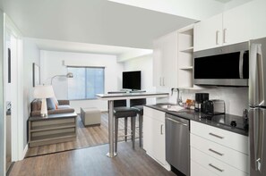 A modern kitchen with a dining area, built-in appliances, and a large window.
