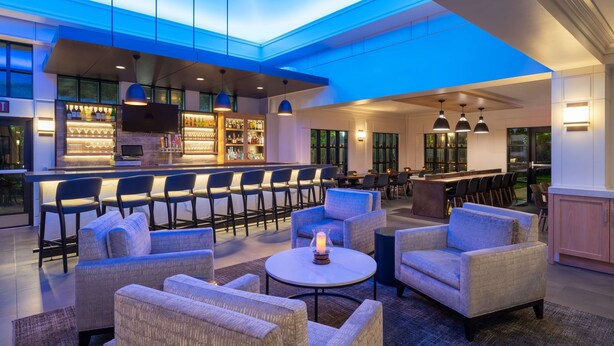 Een ruime lounge met comfortabele zitplaatsen, een bar met een goed gevulde plank en een modern plafondontwerp.