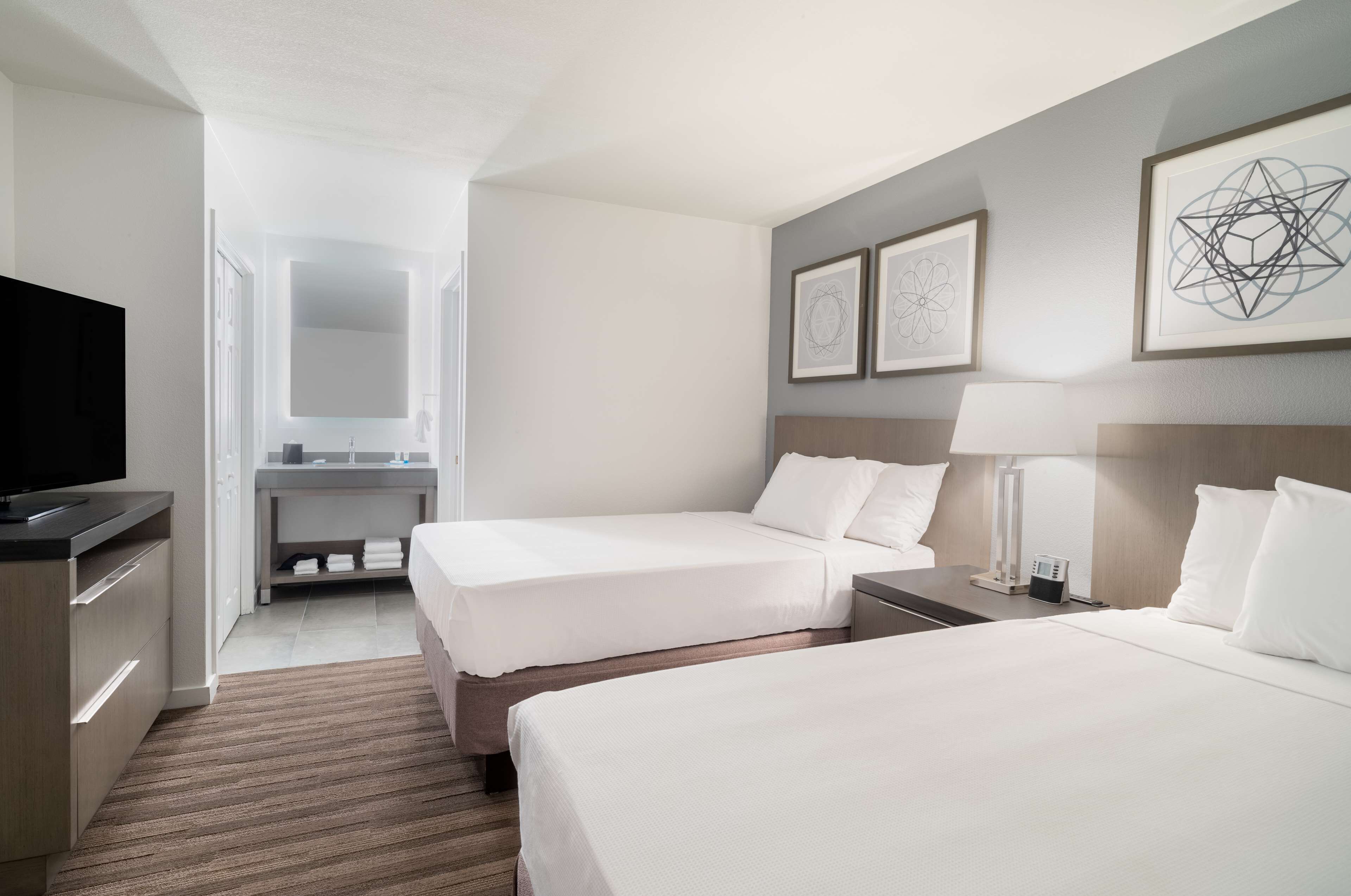 A hotel room with two beds, a TV, a desk, and a bathroom.