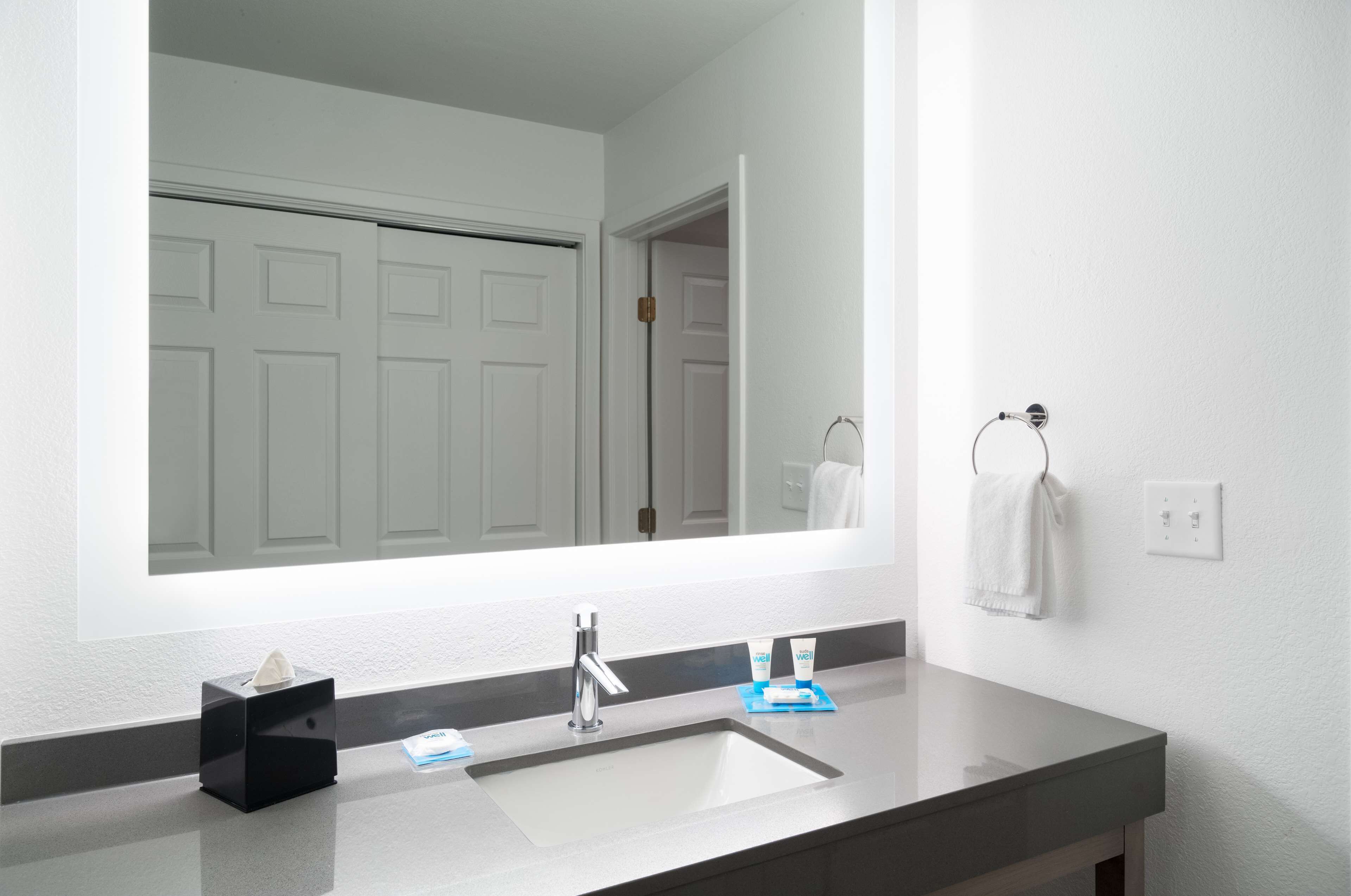 A modern bathroom with a large mirror, a sink, and a towel rack.