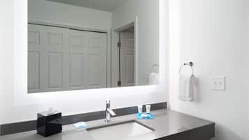 A modern bathroom with a large mirror, a sink, and a towel rack.