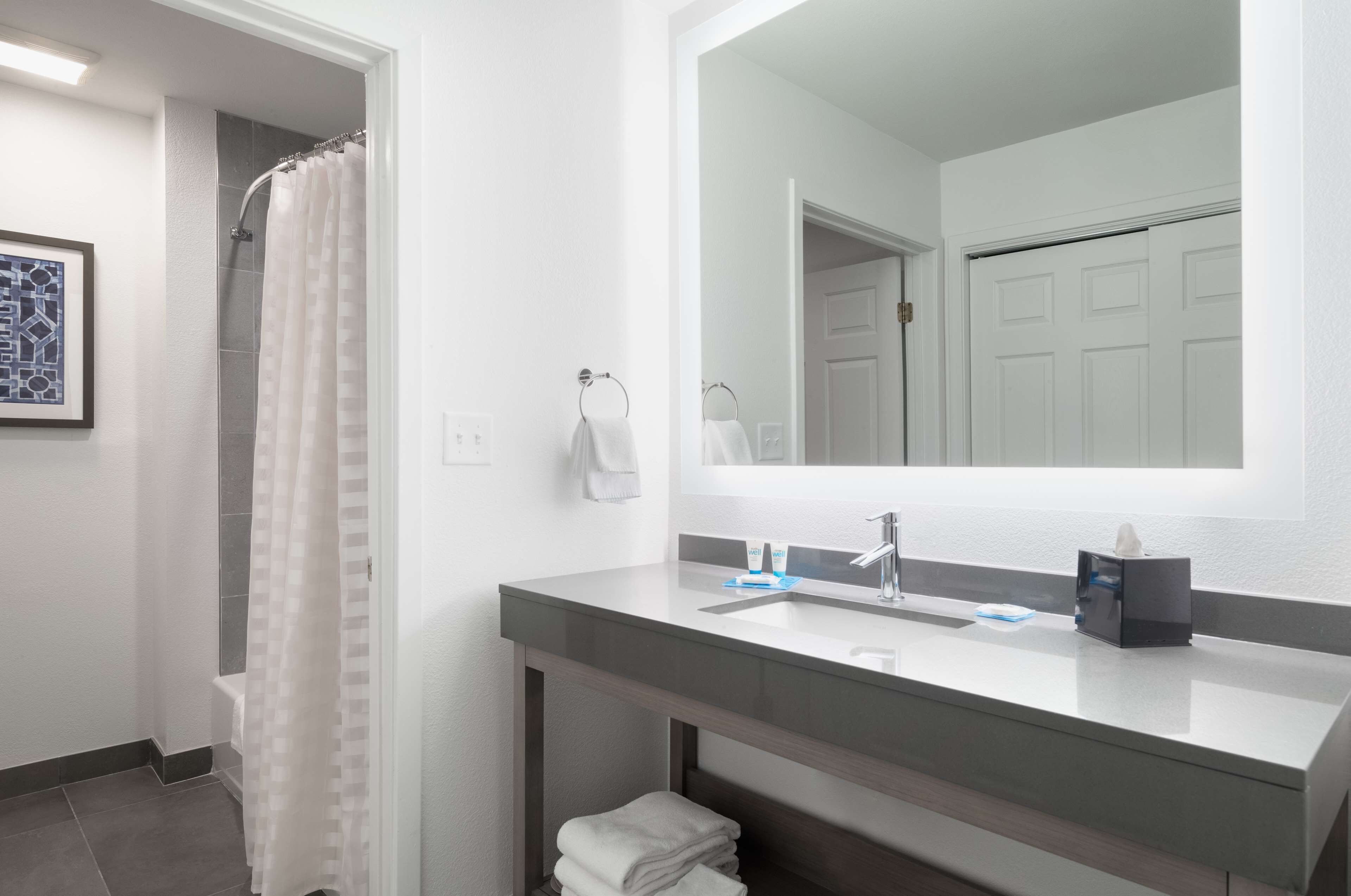 A modern bathroom with a shower, a sink with a mirror, and a towel rack.