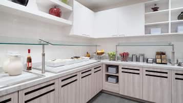 A modern kitchen with white cabinets, a marble countertop, and a glass display case.
