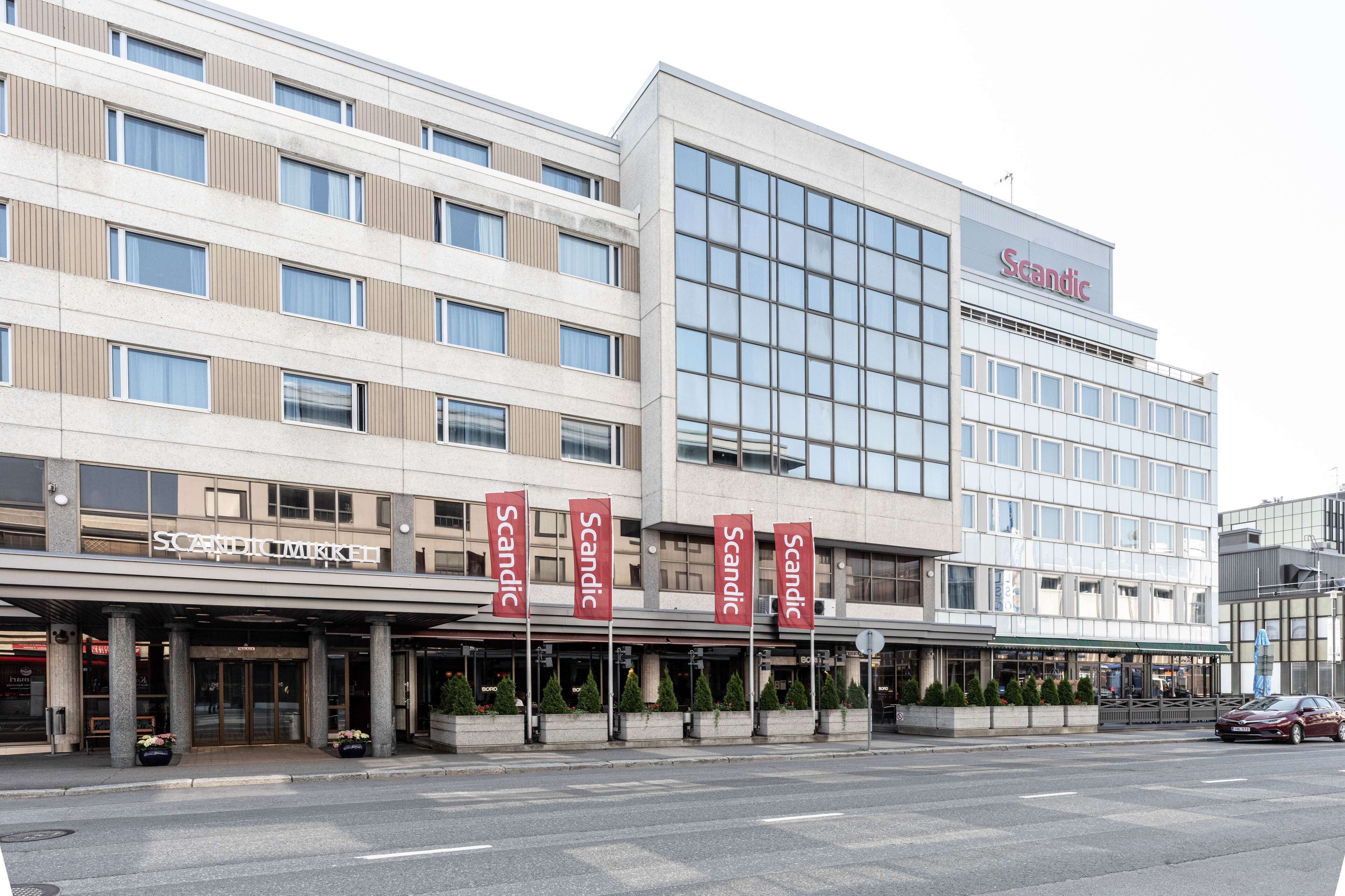 Un hôtel moderne à la façade sobre, doté de nombreuses fenêtres et d’une enseigne « Scandic » bien visible.