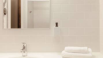A bathroom with a white sink, a modern faucet, a mirror, and a towel.