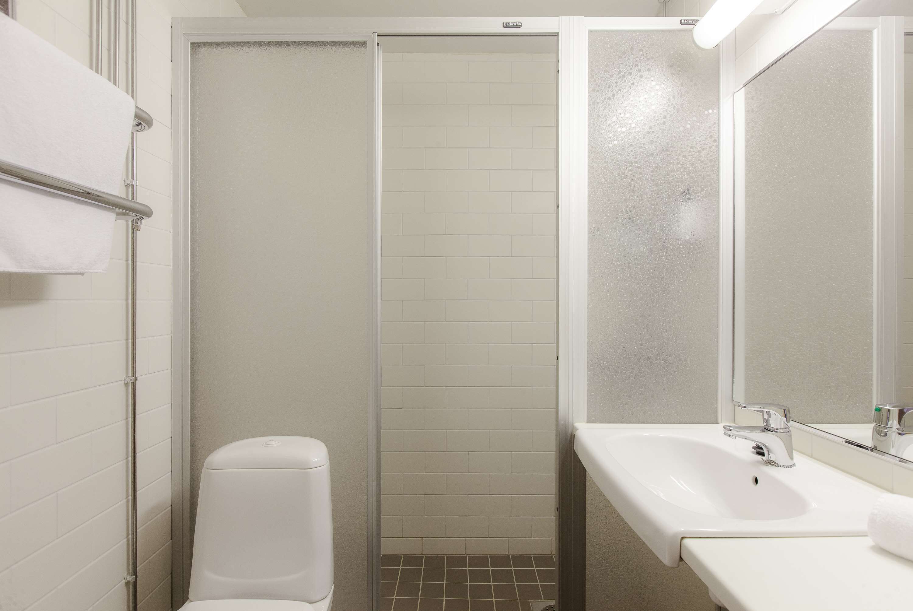 A bathroom with a white sink, a mirror, and a toilet.
